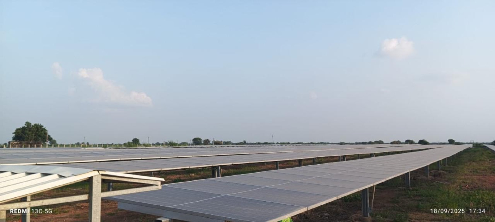 Long diagonal rows of ground-mounted bifacial solar modules receding toward the horizon at a commissioned utility-scale plant.