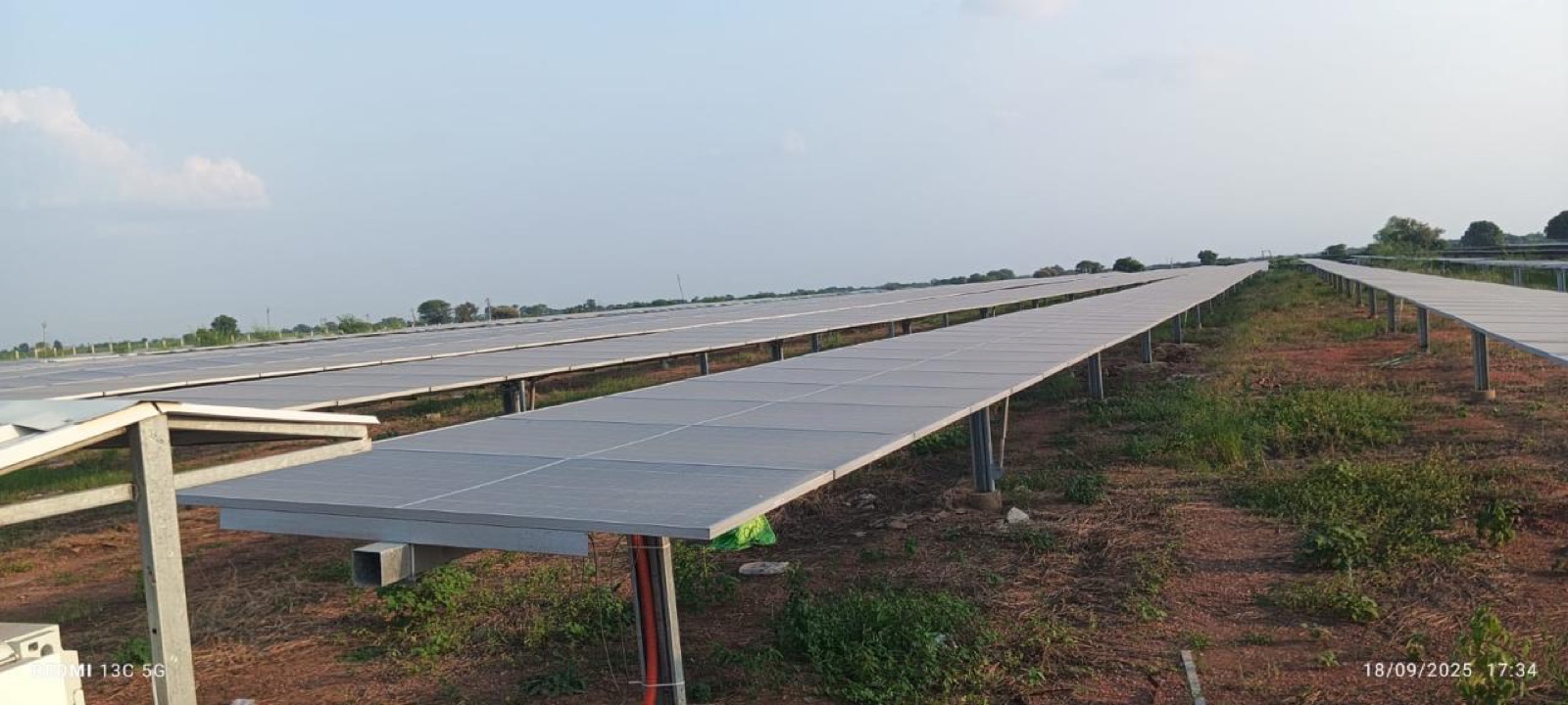Close view of bifacial module tables on steel structure across grassy ground.