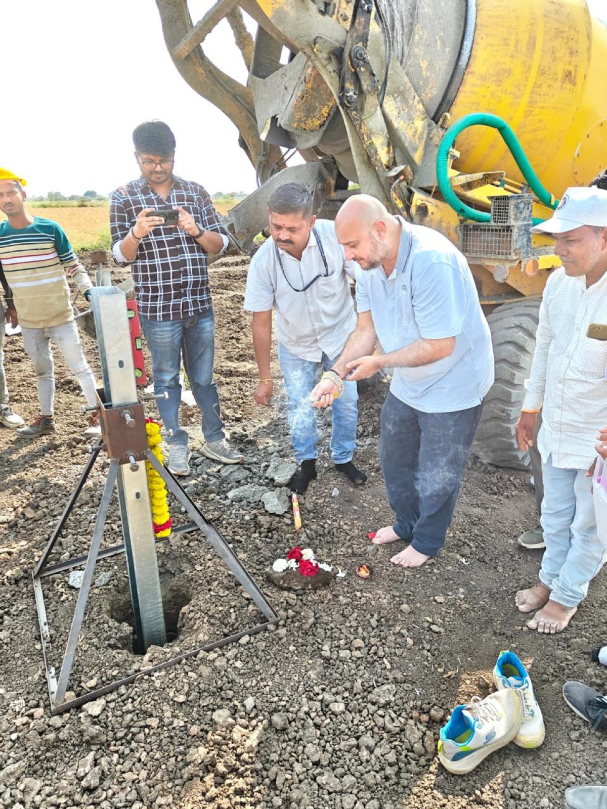 A groundbreaking ceremony at a solar site: the team gathered around the first pile foundation with a concrete mixer behind.