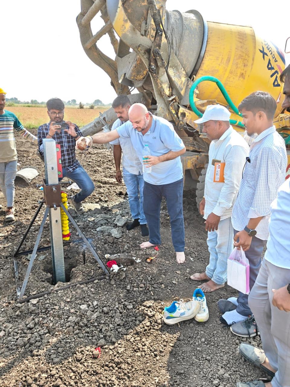 Work begins as concrete is placed at the first pile foundation, team looking on.